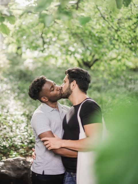 two men kissing in the park
